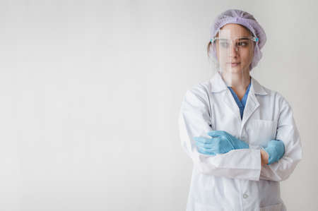 Female doctor wearing protective mask using infrared thermometer to check body temperature on white backgroundの写真素材