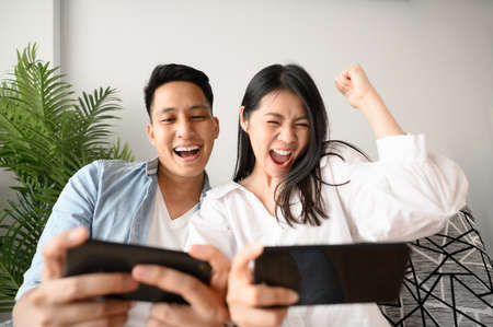 Happy Asian couple hugging and enjoying a good time together with red rose in hand on valentine day...