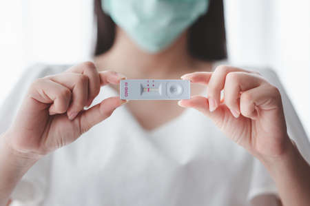 Close up shot of women wearing medical face mask showing  test strip with negative result in handの写真素材