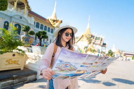 Happy Asian woman with a guide map and a backpack travelling in Thailandの写真素材