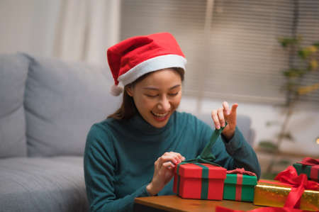 Happy Asian woman using smartphone mobile taking selfie with Christmas gift box with Christmas tree in backgroundの写真素材
