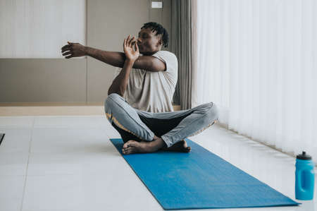 Black Man doing leg stretching exercise at home. workout at homeの写真素材