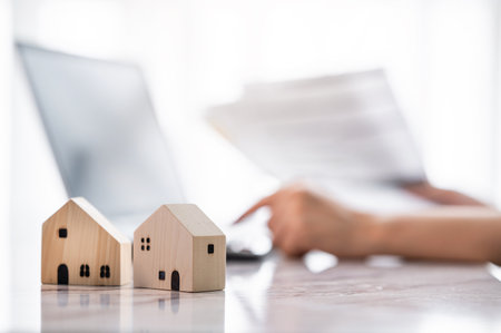 Close up wooden house model with hand using laptop for financial analysis for real estateの写真素材