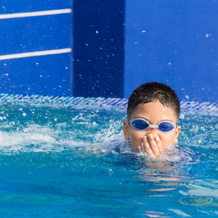 Cute little boy with his goggles on in swimming poolの写真素材