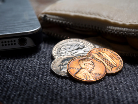 US dollar coins placed outside the wallet with smartphone.の写真素材