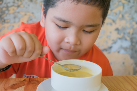 Cute Asian boy eating mushroom soup.の写真素材