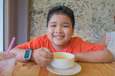Cute Asian boy eating mushroom soup.の写真素材