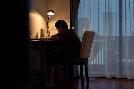 Asian boy doing homework on the table in the evening.の写真素材