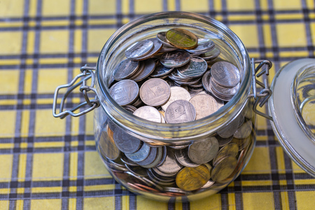 Many coins in glass jar, saving.