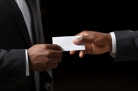 cropped shot of businesspeople exchanging business card isolated on black backgroundの素材