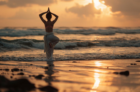 Young woman practicing yoga on the beach at sunset. Healthy lifestyle concept.の素材