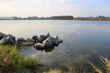 rocky lake with some stones and grass in the bank near Ho Chi Minh city, vietnamの写真素材