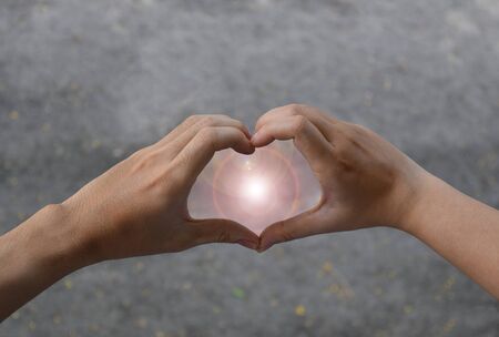 Hands in shape of love heart with sunの写真素材