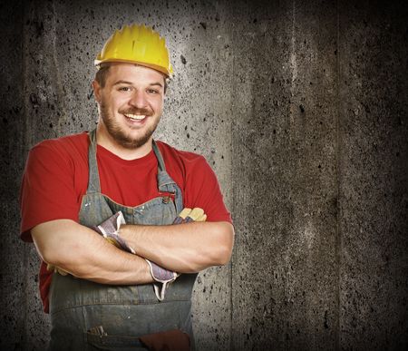 fine portrait of caucasian smiling handyman with grunge concrete backgroundの写真素材