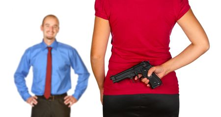 young caucasian man come back home and angry wife waiting for him with gun behind her backの写真素材