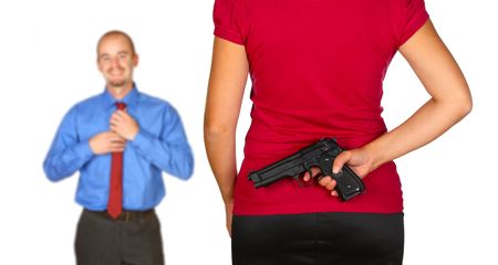 young caucasian man come back home and angry wife waiting for him with pistol behind her backの写真素材