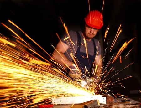 handyman with electric grinder on duty, industrial backgroundの写真素材