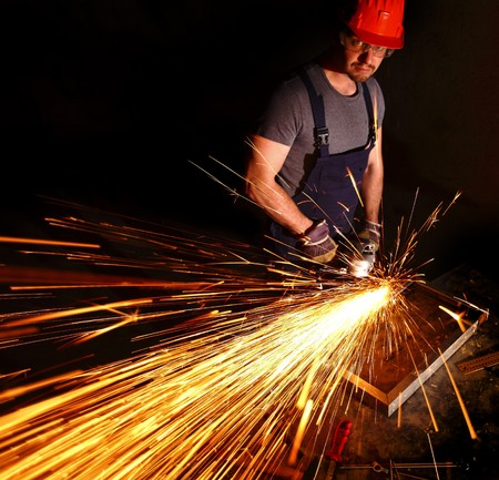 caucasian labor work with electric grinder on metal part