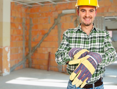 happy handyman wearing protection gloves in construction site