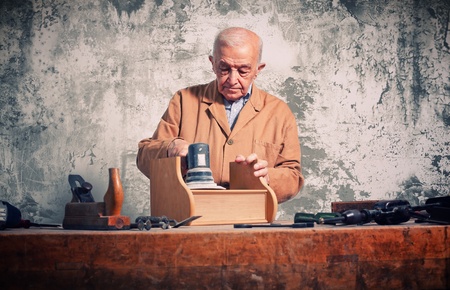man at work with electric grinder on wood furniture partの写真素材