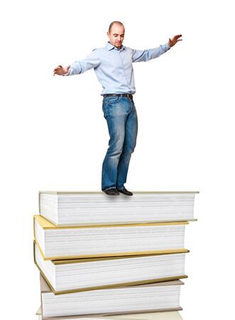 young man try to balance on book pileの写真素材