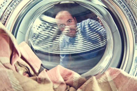 portrait of man view from washing machine insideの写真素材