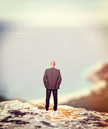 standing businessman on cliff looking the seaの写真素材