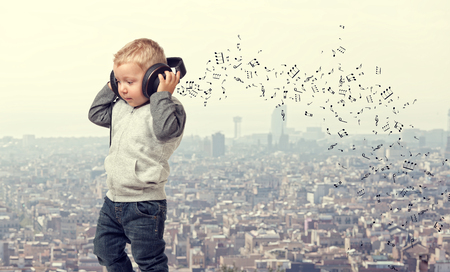little child with headphone and modern town backgroundの写真素材