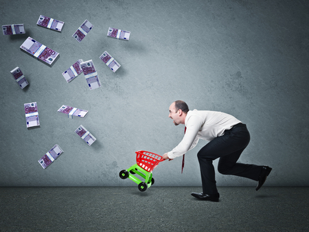 man with toy trolley and fallen euro moneyの写真素材