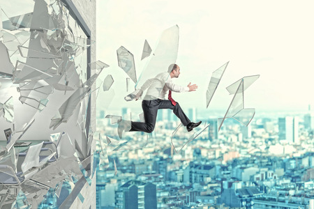 businessman jump outside his office breaking windowの写真素材