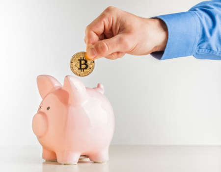 man put bitcoin coin in classic pink piggybank 