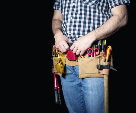 detail of handyman with leather toolsbelt and tools on dark backgroundの写真素材
