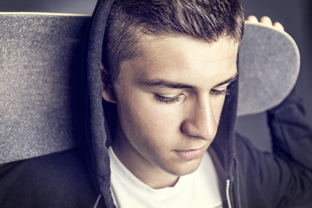 portrait of skateboarder with board behind his head