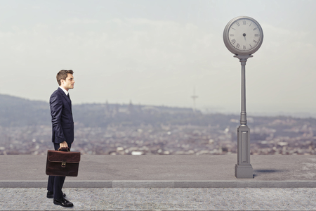 standing businessman with handbag and clock without hands, time conceptの写真素材