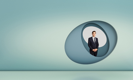 standing businessman and abstract modern wall with copyspaceの写真素材