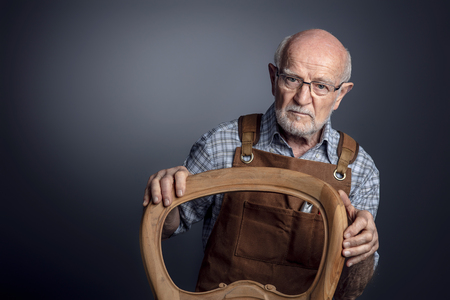 portrait of senior caucasian craftsman with unfinished chairの写真素材