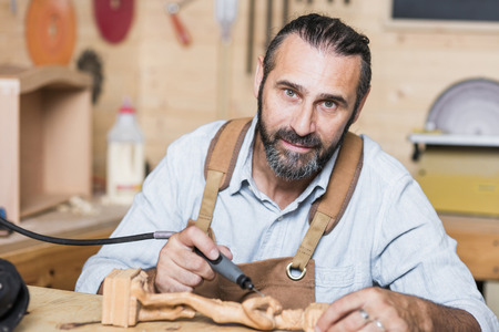 caucasian carpenter at work in a workshop with drillの写真素材