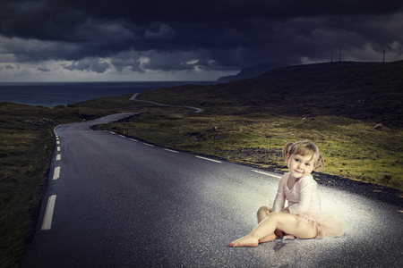 adorable kid with ballet clothes sit on long lonely roadの写真素材