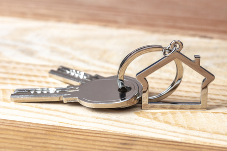 keys and keychains in the shape of a house on a wooden background