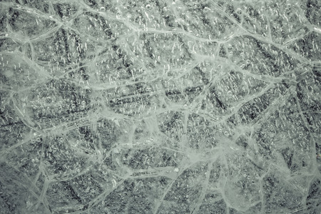 detail of a cracked ice texture with air bubbles trapped inside.