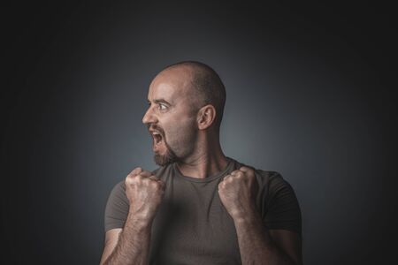 Man posing as a winner and with a head in profile. Studio shot. Concept of victory and success.
