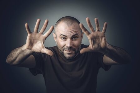 studio portrait of a man in a shirt with open hand position as if he were performing magic.