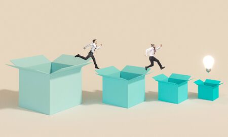 business people jump from one box to another to reach the light bulb that represents the winning idea. concept of competition in work and creativity.の写真素材