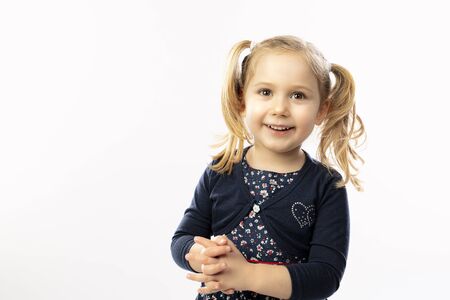 Studio portrait of a 3 year old blond girl with a happy and positive expression.