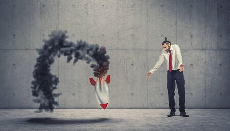 businessman looks at the failure of the takeoff of a vintage rocket with smoke and flames. concept of false start, failure, crisis.の写真素材