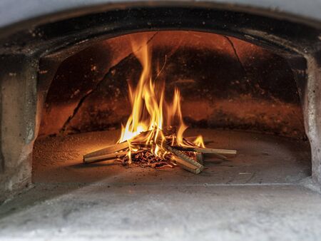 lighting the fire of a wood-fired pizza oven.の写真素材