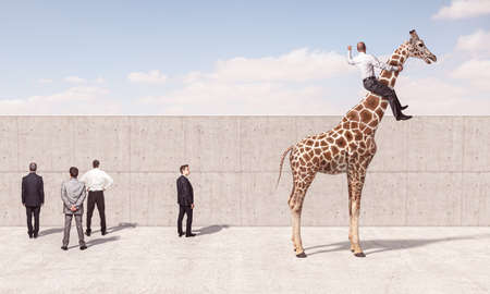 man rides a giraffe to see beyond the wall. Concept of out of the box thinking.の写真素材