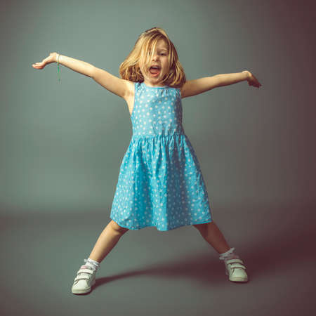 happy little girl with open arms on gray background, studio photo.の写真素材