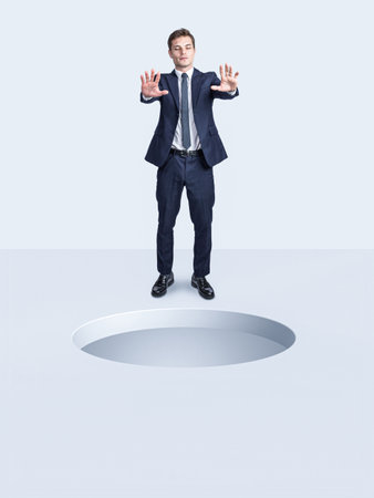 blindfolded businessman and big hole in the ground in front of him. danger concept.の写真素材