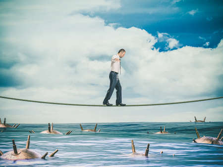 businessman walks on a tightrope over a sea full of mines. concept of risk and danger.の写真素材